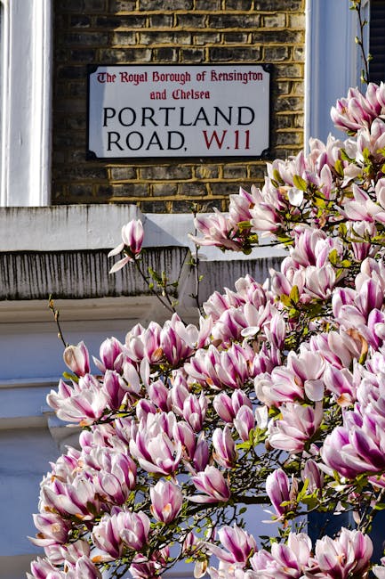 A white residential building with a decorative balustrade on the front porch, featuring three paired columns and a smooth, painted wall. Mounted on the wall is a street sign reading 'Portobello Road, 