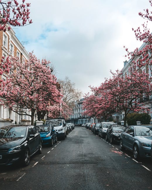 The image shows a row of white terraced houses with black wrought iron railings along the pavement in Kensington. In front of the buildings, there is a blue bicycle leaning against one of the railings